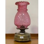 A late Victorian brass oil lamp with moulded cranberry glass shade H48cm