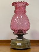 A late Victorian brass oil lamp with moulded cranberry glass shade H48cm