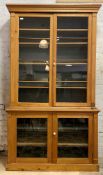 A 19th century pine two part cabinet, the top section with twin glazed doors enclosing three