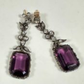 A pair of white metal amethyst glass cushion cut pendant earrings on paste set leaf supports and