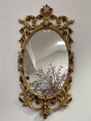 A Rococo style cast gilt metal oval wall hanging mirror decorated with scrolling acanthus 74cm x