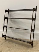 An early 20th century mahogany four height open wall hanging shelf with pierced panel end supports