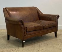 A contemporary two seat sofa, upholstered in tan brown studded leather, raised on square tapered and