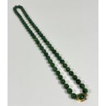 A spinach green jadeite bead necklace with silver gilt fastening set jadeite oval panel (each