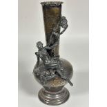 An Epns hammered bottle neck style vase mounted with a winged fairy and cherub, raised on circular