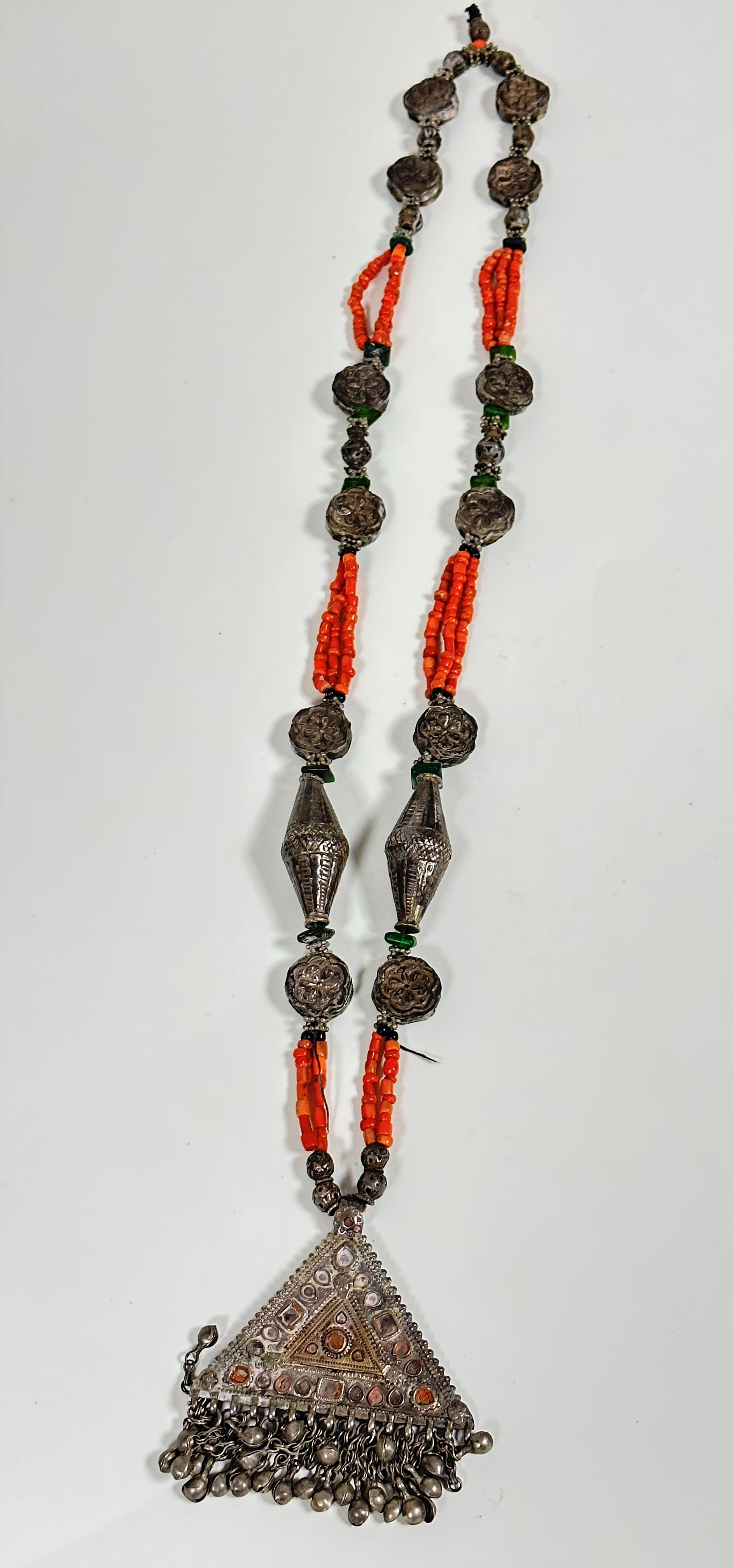 A Middle Eastern necklace set white metal discs and green glass beads, with triple strand pink coral