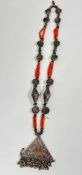 A Middle Eastern necklace set white metal discs and green glass beads, with triple strand pink coral