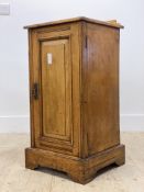An Edwardian ash bedside cupboard, the panelled door enclosing one shelf, raised on a shaped