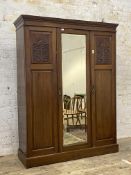 An Edwardian mahogany triple wardrobe, the dentil cornice over centre bevelled mirror door and