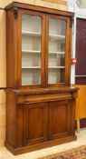 A Victorian mahogany bookcase on cabinet, the top section with twin glazed doors enclosing three