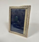 A sterling silver rectangular photograph frame with chased scrolling leaf decoration (16cm x 21cm,