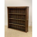 An early 20th century oak open bookcase, the frieze incised with trailing foliate, and oak leaf