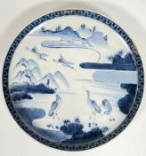 A 19th century Japanese blue and white plate decorated with scene of cranes and mountains, with