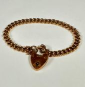 A gilt metal flat curb link bracelet mounted with 15ct gold heart shaped padlock (7cm)