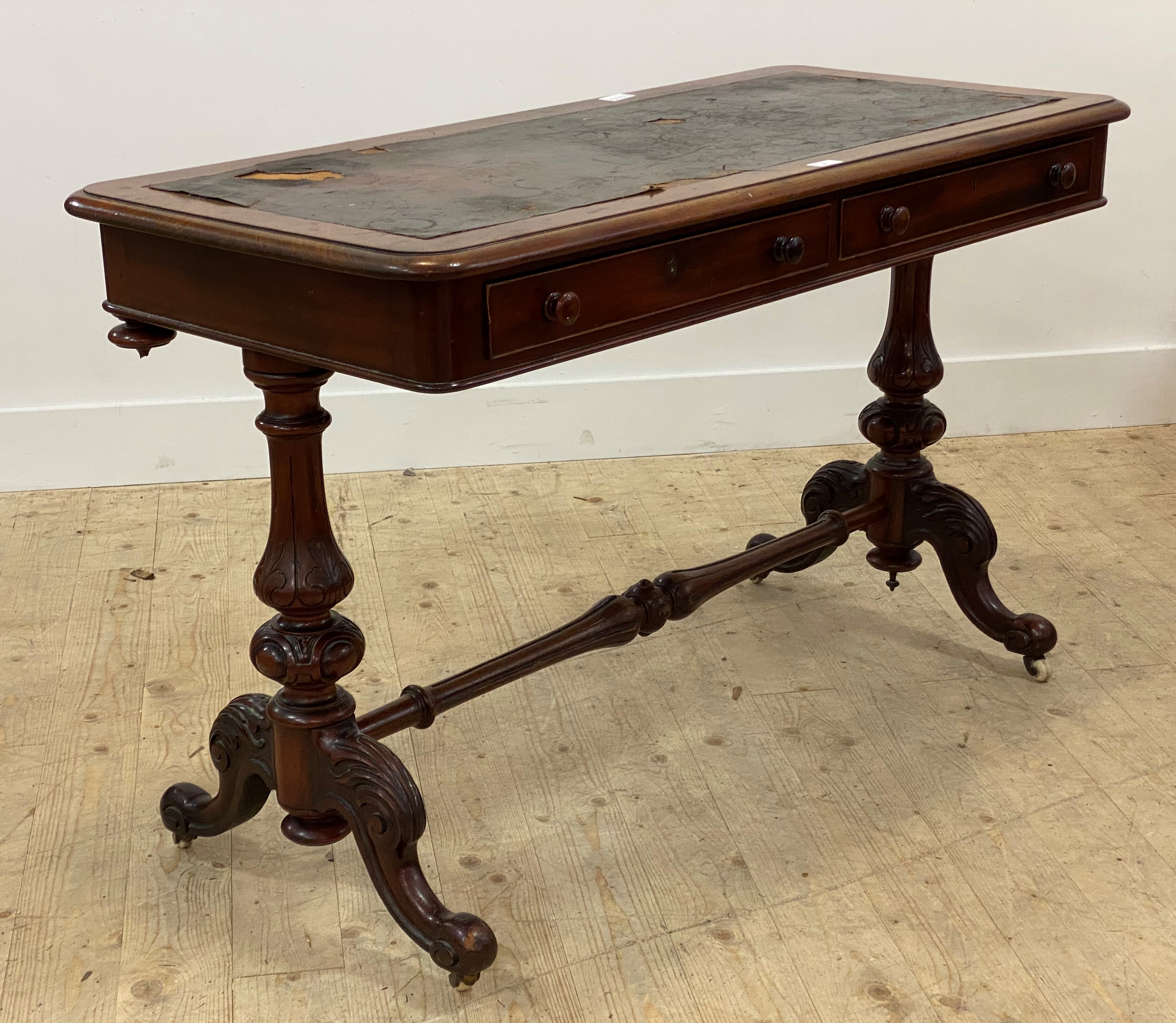 A Victorian mahogany library table, the skivered top (A/F) over two frieze drawers, raised on leaf