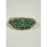 A 9ct gold emerald and diamond cluster ring, bombe, three rows of emeralds, with diamond points (P/
