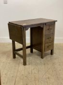 An early to mid 20th century oak typists desk, the top with drop leaf to one end over slide and