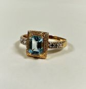 A modern 10ct gold dress ring mounted cushion cut aquamarine in yellow metal claw setting, flanked