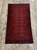 An Afghan Bokhara rug, the red field with two rows of guls within a multi line border 190cm x 101cm