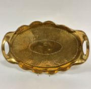 An Edwardian brass Arts & Crafts style scalloped two handled brass tray with hammered central oval