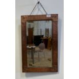 An Arts and Crafts period hammered copper framed wall hanging mirror with bevelled plate 35cm x