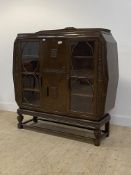 An Art Deco period carved oak display cabinet, centred by a fall front cupboard above another