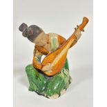 A Chinese pottery Musician figure playing an instrument, decorated with brown treacle and green