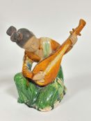 A Chinese pottery Musician figure playing an instrument, decorated with brown treacle and green