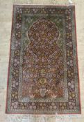 A Persian design silk prayer rug, the red and green field with repeating flower heads, within a blue