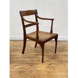 A Regency period yew wood elbow chair, the crest rail inlaid with ebony bands, above reeded open