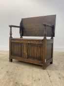 An oak monks bench of 18th century design, the folding top over open arms with turned columns,