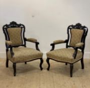A pair of Late Victorian stained walnut drawing room armchairs, with scroll carved and upholstered
