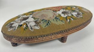A Victorian treen oval foot rest with reeded moulded edge upholstered in beaded floral tapestry