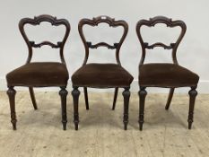 A set of three mid 19th century rosewood dining chairs, the crest and rail of conforming scrolls