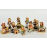 A collection of nine German Hummel pottery figures including two seated boys with instruments,