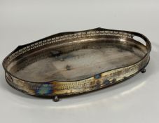 An Epns oval scalloped gallery two handled drinks tray on claw and ball feet with all over scrolling