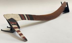 An Australian Aborigine hooked boomerang with painted decoration, with bands of black, white and red