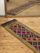 A Suzani kilim runner rug of repeating lozenge design within a running dog border 265cm x 62cm