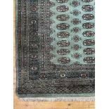 A green ground Bokhara type rug, the field with multiple rows of guls within a multi line border