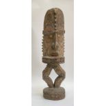 A carved wooden standing figure, Papua New Guinea, with cowrie shell eyes, elaberate headdress and