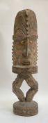 A carved wooden standing figure, Papua New Guinea, with cowrie shell eyes, elaberate headdress and