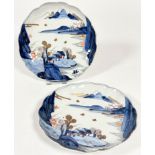 A pair of Japanese Imari scalloped dishes with landscape scenes of shore and mountains, decorated in