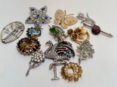 A collection of paste set brooches including a Cartier style Flamingo brooch, Peacock brooch,