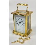 A Matthew Norman brass four glass clock with folding handle to top, white enamel dial and roman