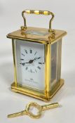 A Matthew Norman brass four glass clock with folding handle to top, white enamel dial and roman