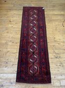 A Persian Baluchi runner rug, the red ground with pole medallion within a border 235cm x 171cm