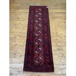 A Persian Baluchi runner rug, the red ground with pole medallion within a border 235cm x 171cm