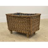 A small wicker laundry basket with floral printed cotton lining to interior and moving on castors