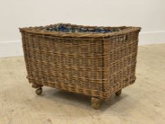 A small wicker laundry basket with floral printed cotton lining to interior and moving on castors