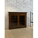 A 19th century bookcase, the twin glazed doors opening to three shelves, raised on later bun